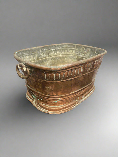Antique, square, copper planter with large ring handles and a cast oval design.