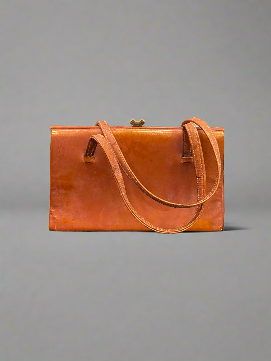 Vintage orange leather handbag with a brass clasp.