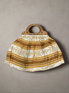 Vintage bag with a brown, mustard and white pattern fabric and wooden handle.