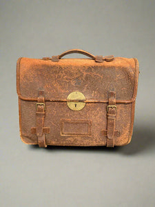 A heavily aged vintage brown leather satchel with a brass lock.