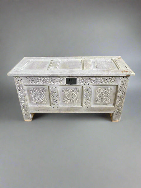 Distressed white wooden chest with intricate carved patterns.