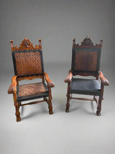 A pair of Spanish renaissance-style throne chairs with embossed leather backs and a central carved rosette.