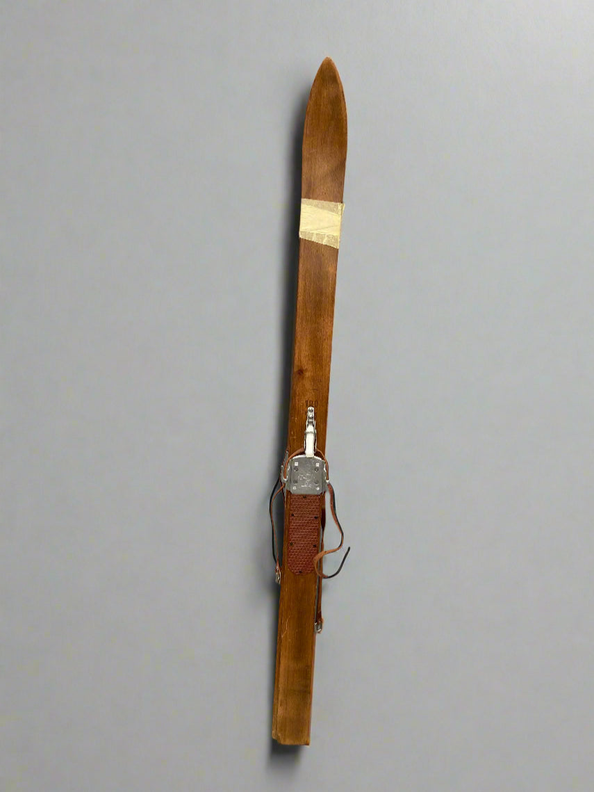 A pair of shorter vintage wooden skis.