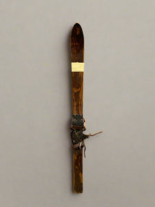 A pair of shorter vintage wooden skis with a dark stain.