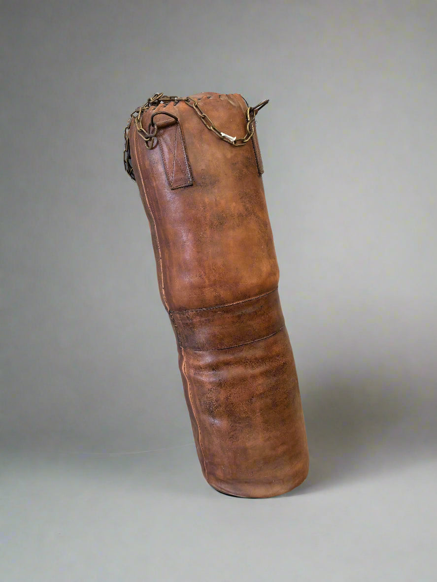 A vintage brown leather punching/boxing bag.