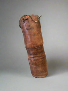 A vintage brown leather punching/boxing bag.
