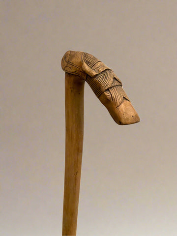 A large wooden walking stick with a carved horse head handle.