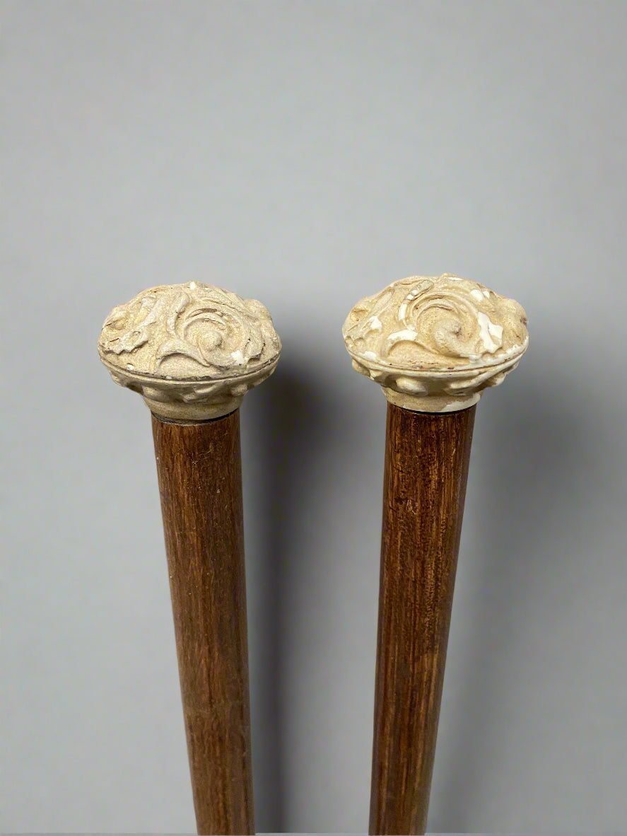 A matching pair of brass tipped wooden walking sticks, with carved stone tops.