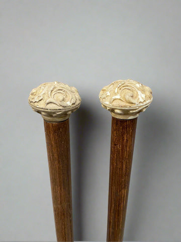 A matching pair of brass tipped wooden walking sticks, with carved stone tops.