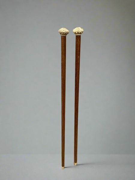 A matching pair of brass tipped wooden walking sticks, with carved stone tops.