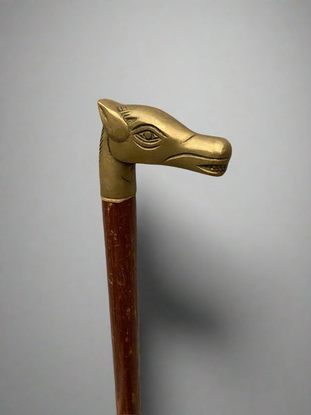 A wooden walking stick with a cast brass horse head handle.