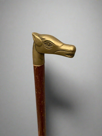 A wooden walking stick with a cast brass horse head handle.
