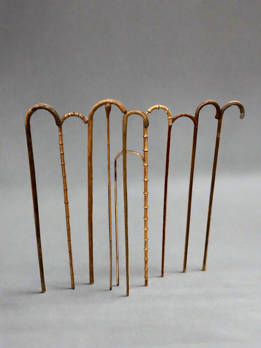 A collection of natural wooden canes with curved crook handles.