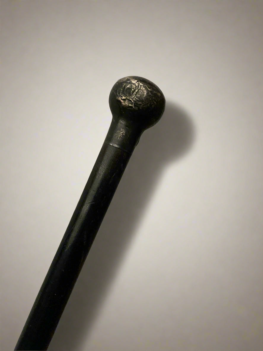 A sleek ebonised walking stick with a black metal ball top.