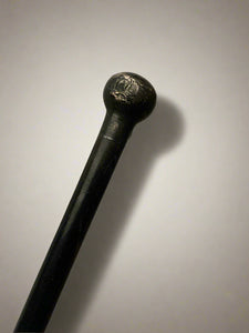 A sleek ebonised walking stick with a black metal ball top.