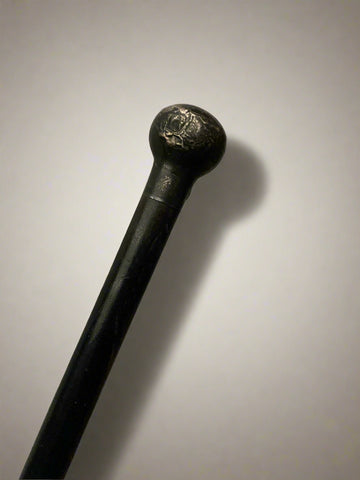 A sleek ebonised walking stick with a black metal ball top.