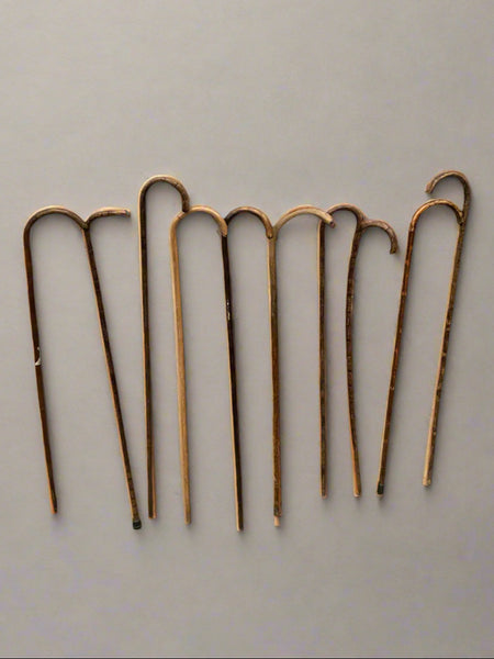 A collection of simple, natural, wooden canes with a curved crook handle.