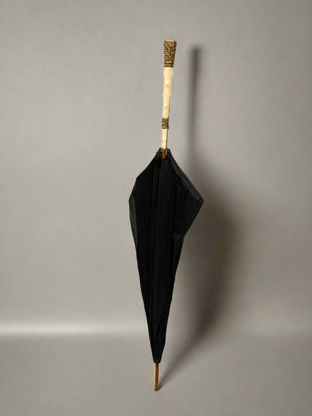 A black parasol with an ivory and gold mounted handle, circa 19th century.