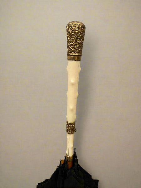 A black parasol with an ivory and gold mounted handle, circa 19th century.