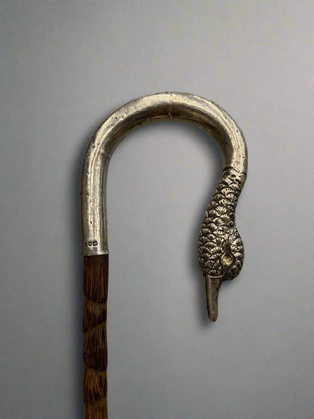 An elegant umbrella with a black parasol and cast silver swan head handle.