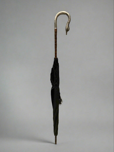 An elegant umbrella with a black parasol and cast silver swan head handle.