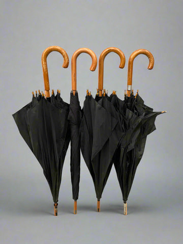 A large collection of classic black umbrellas with wooden crook handles.