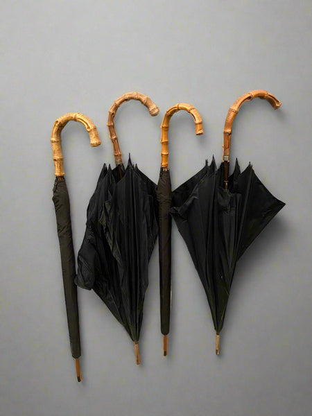 A set of classic black umbrellas with thick whangee bamboo crook handles.