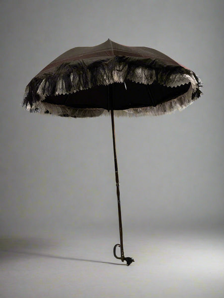 A Victorian black silk mourning parasol with black tassel and white lace fringing.