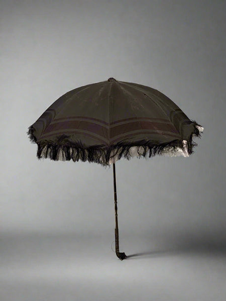 A Victorian black silk mourning parasol with black tassel and white lace fringing.