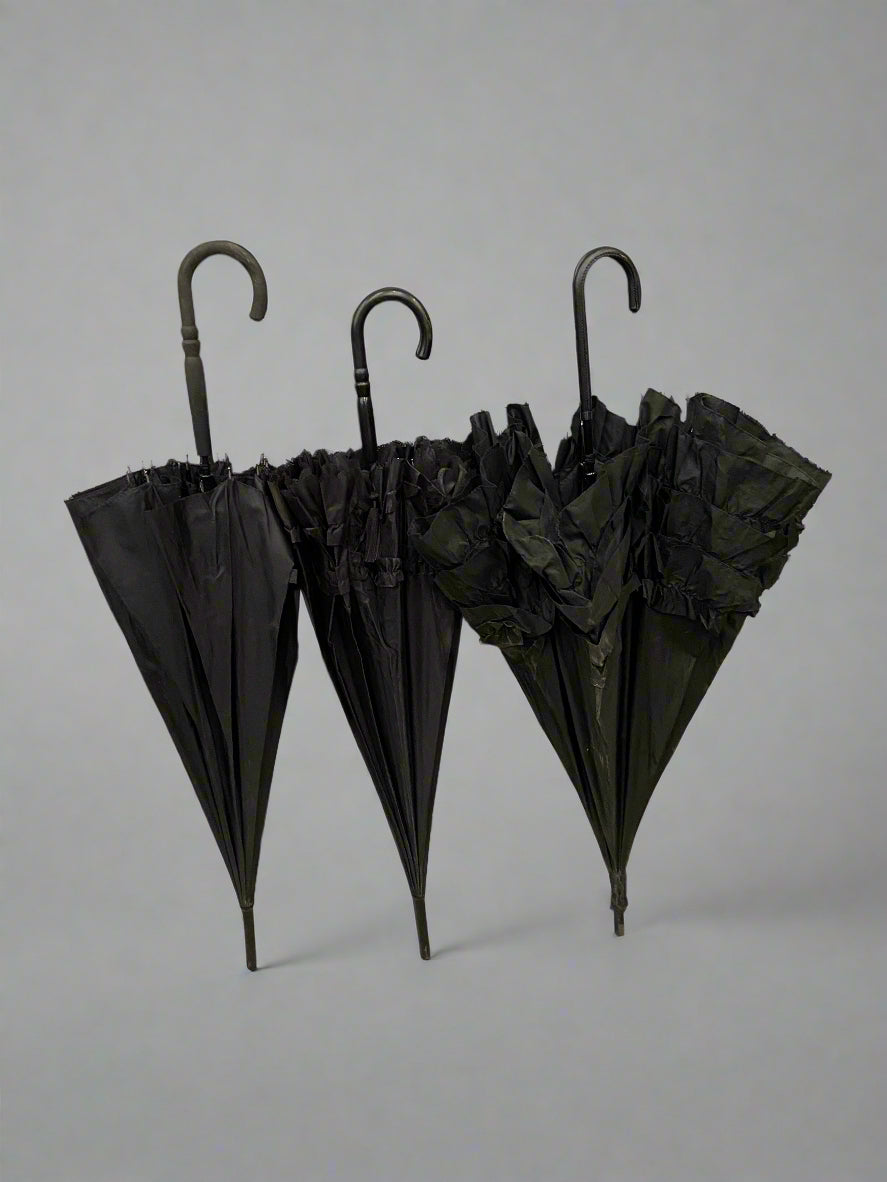 A trio of gothic frilly black parasols with black crook handles.