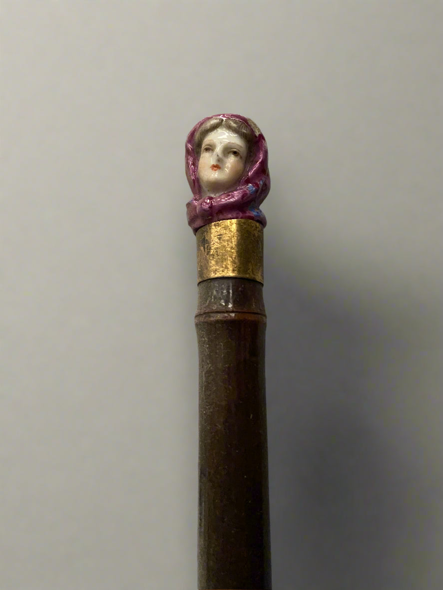A red fabric umbrella topped with an elegant ceramic lady's head.