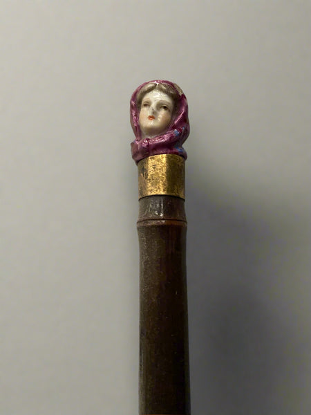A red fabric umbrella topped with an elegant ceramic lady's head.