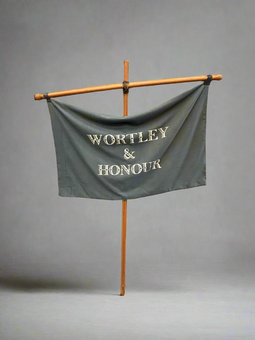 A hand-held banner comprising of a wooden cross and grey fabric printed with the words Wortley & Honour.