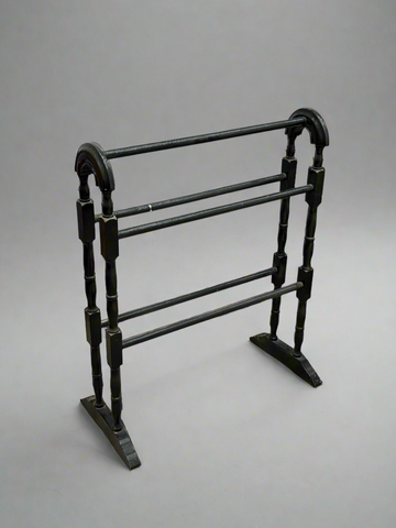 An antique turned black towel rail with a curved frame.
