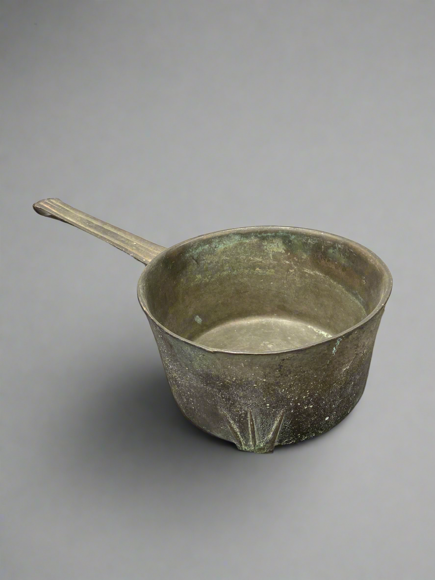 A solid skillet/ cooking pan with metal rests, could be as old as 18th century.