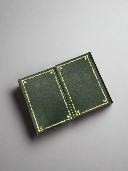 A green leather document holder with a decorative gold embossed border.