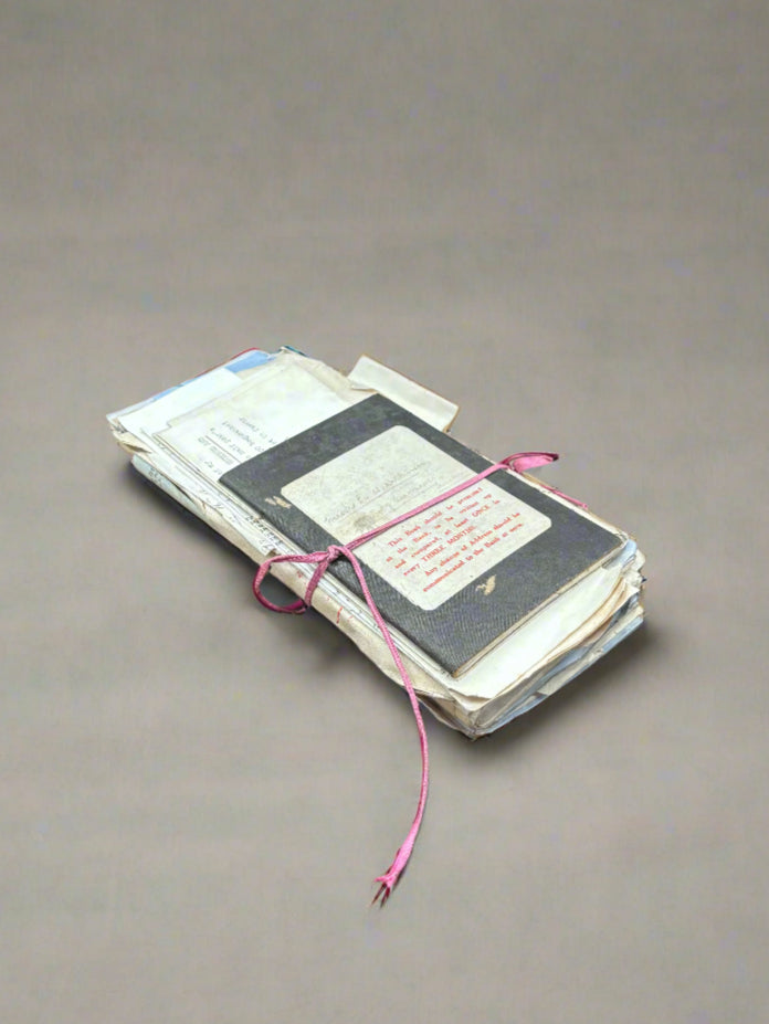 A bundle of period books and papers, tied with a pink ribbon.