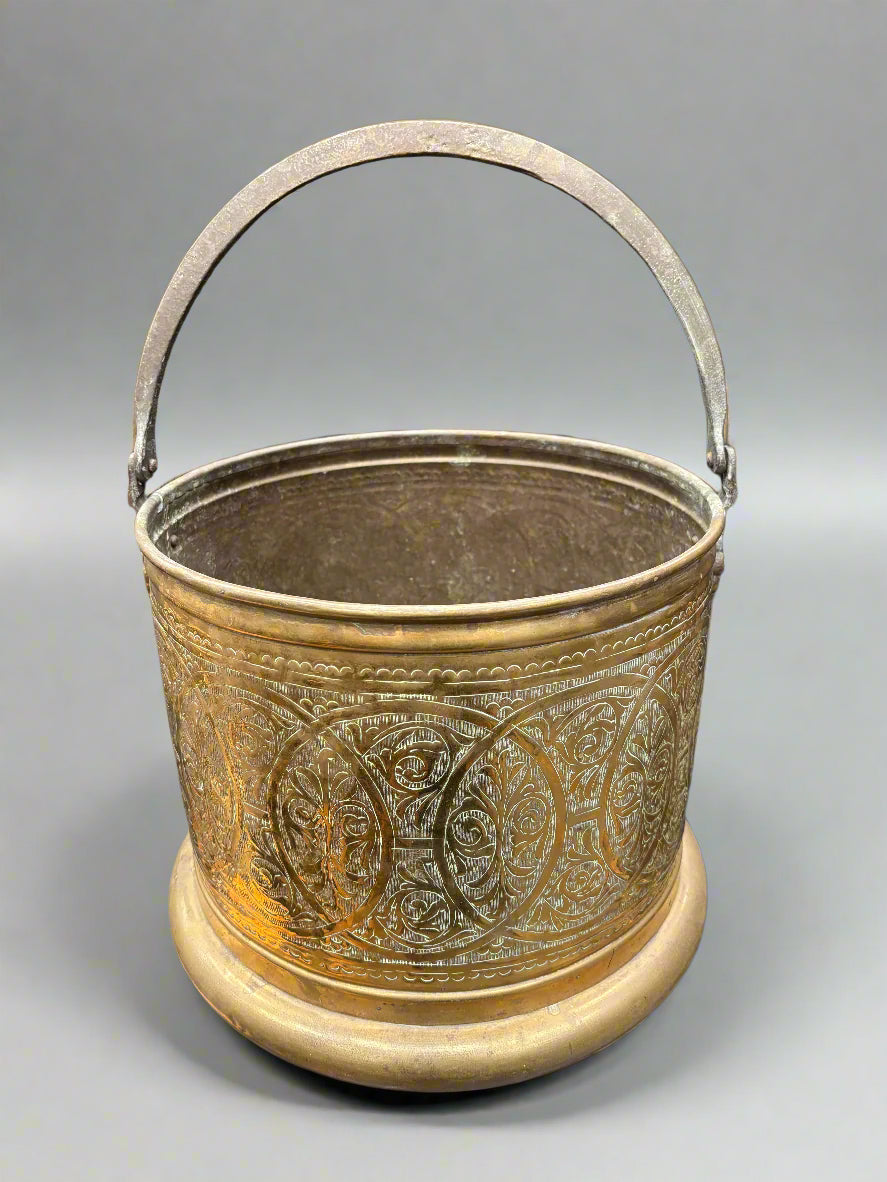 A vintage brass coal pot with an engraved overlapping circle pattern.