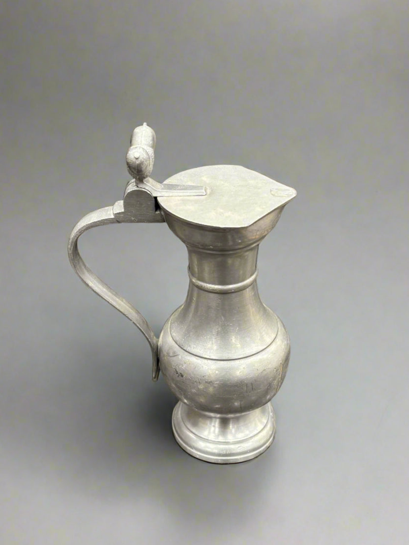 A small, pewter, lidded pitcher jug with cast acorn finials, circa 1890s.