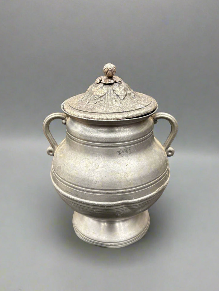 An antique French pewter soup tureen with a wide belly and decorative lid.