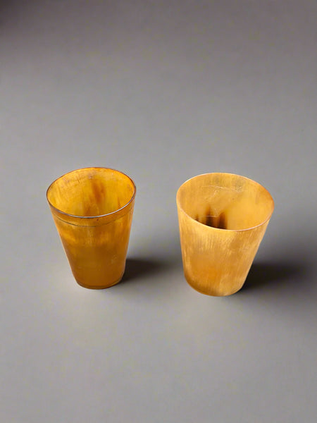 A trio of small, antique, yellow horn shot glasses.