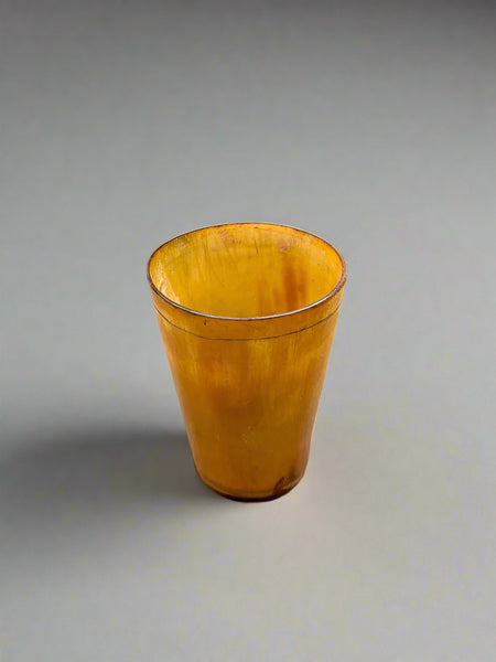 A trio of small, antique, yellow horn shot glasses.