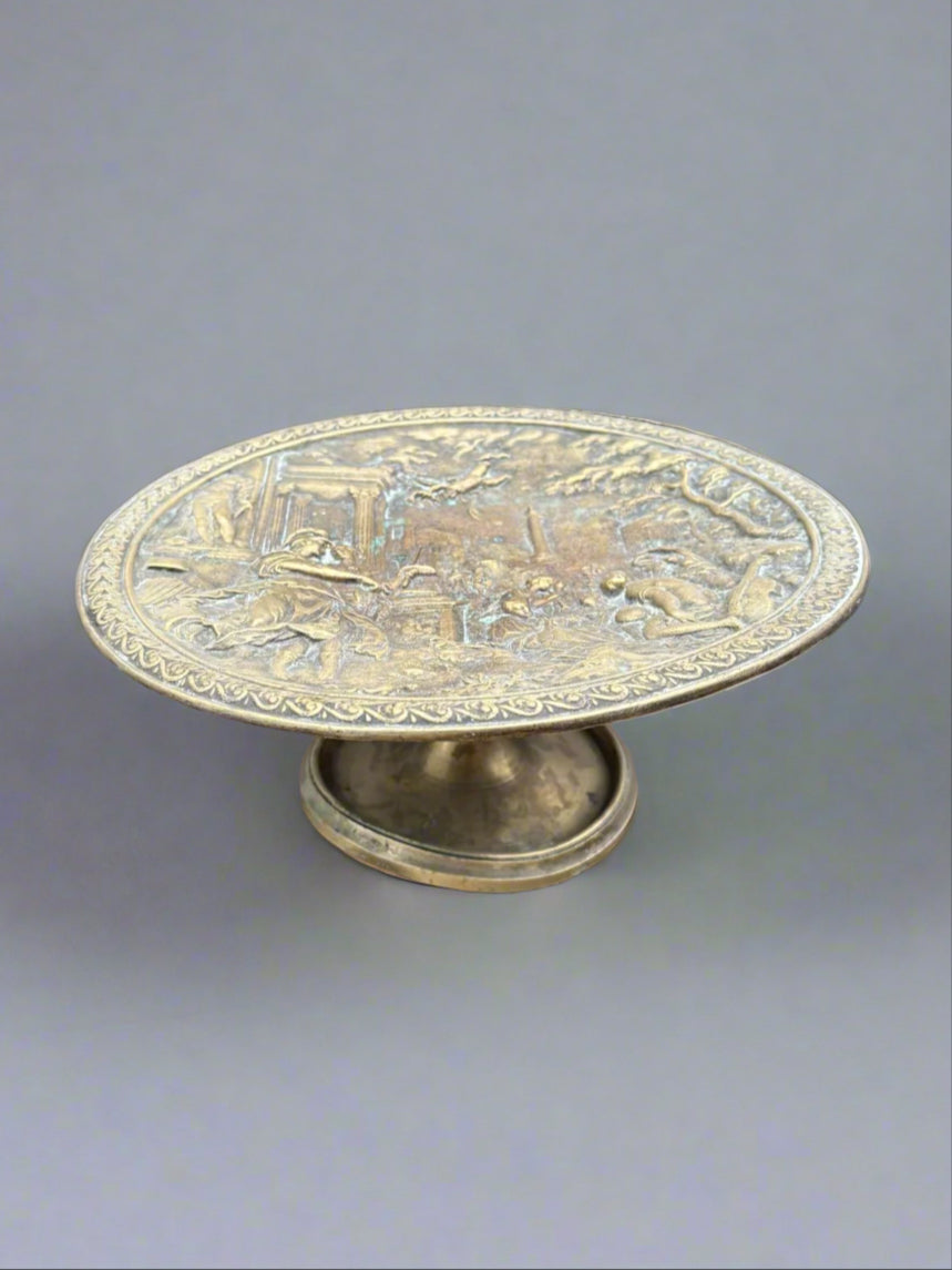 An antique brass tazza fruit plate depicting a Grecian scene, circa 19th century.