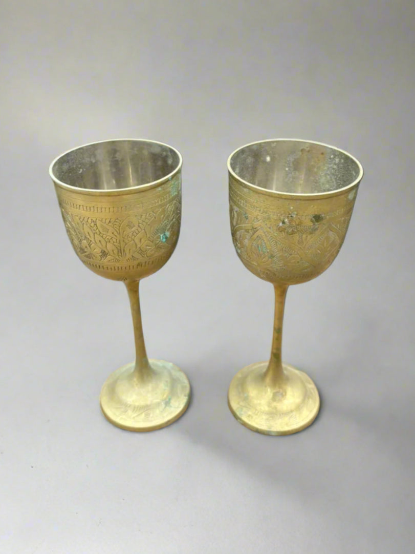 A pair of vintage Indian brass goblets with decorative etched patterns.