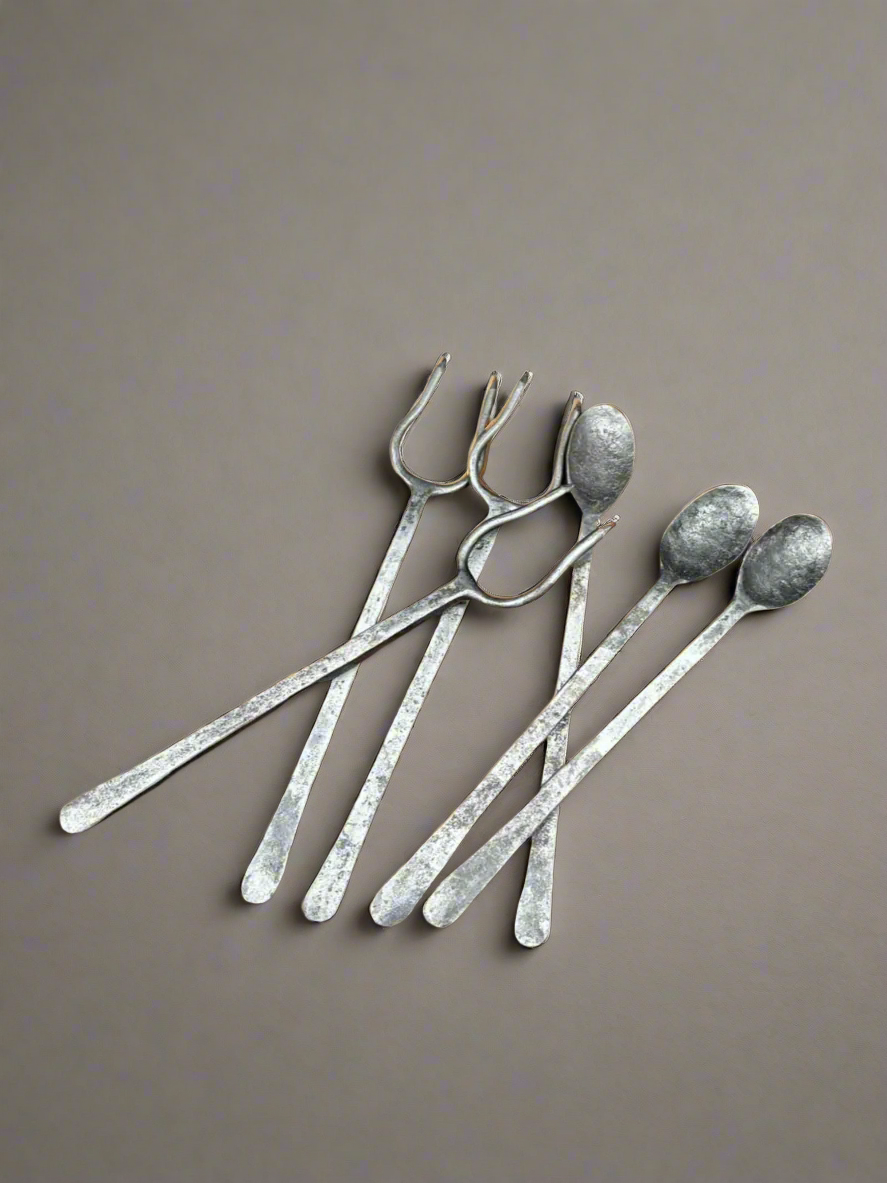 A large set of antique hand forged and hammered cutlery with long handles. The collection includes spoons and meat roasting forks.