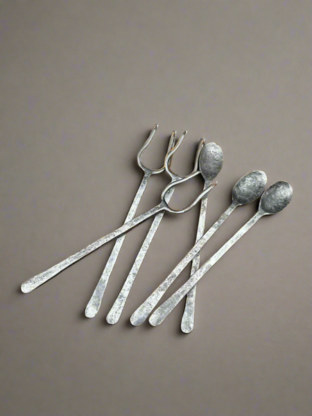 A large set of antique hand forged and hammered cutlery with long handles. The collection includes spoons and meat roasting forks.