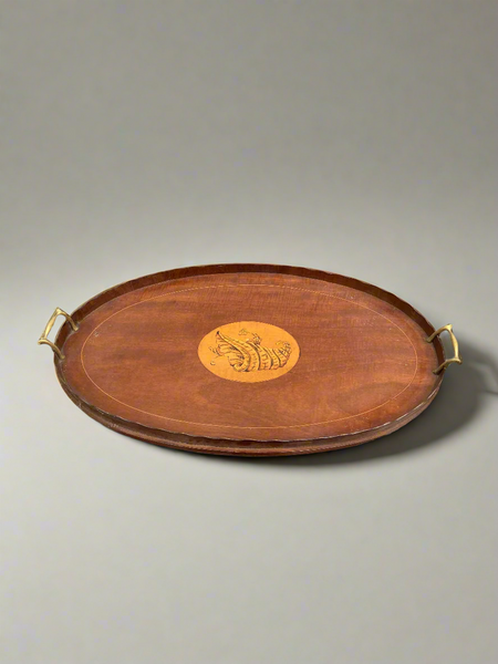 An oval mahogany serving tray with a pie crust edge and a central, decorative, inlaid shell design. Circa 19th century.
