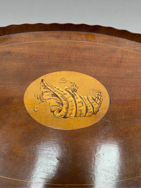 An oval mahogany serving tray with a pie crust edge and a central, decorative, inlaid shell design. Circa 19th century.