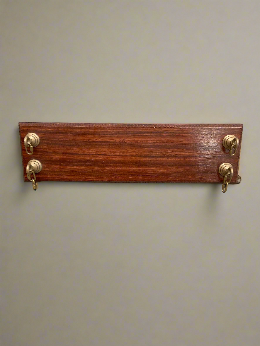 A rectangular wooden board with gold carabiners mounted in each corner.