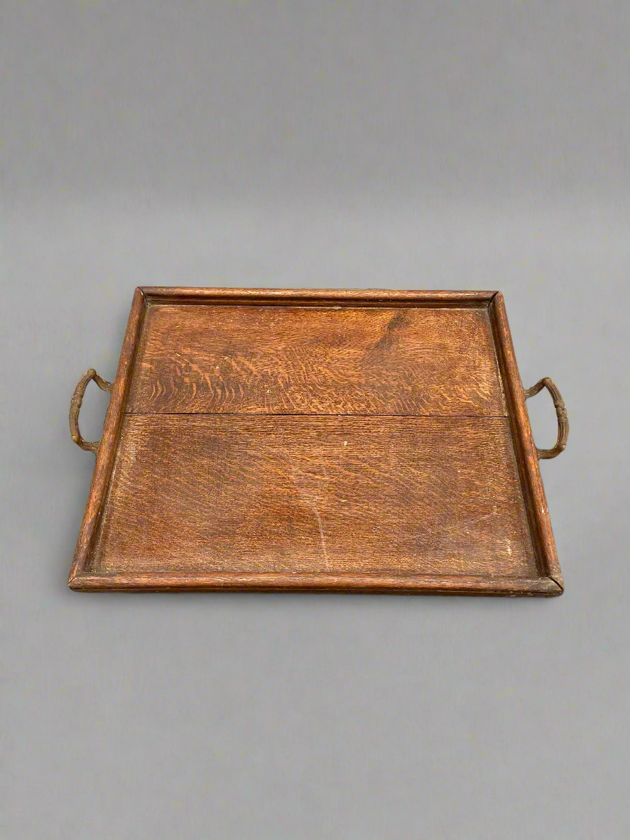 An antique, oak, square serving tray with curved brass handles.